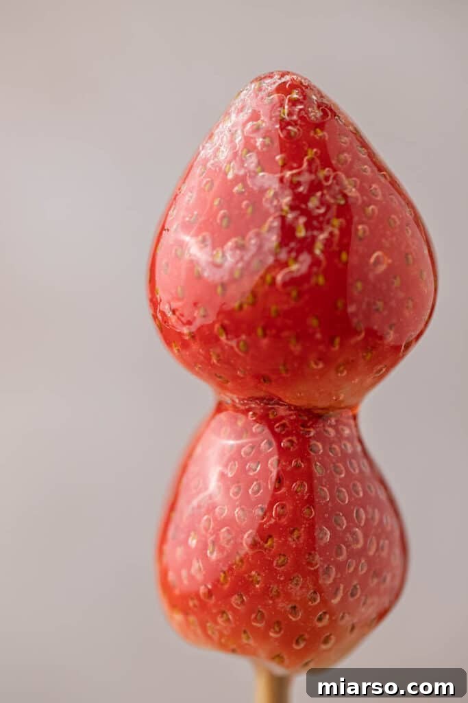 Candied strawberries on a stick, glistening with a perfect sugar coating.