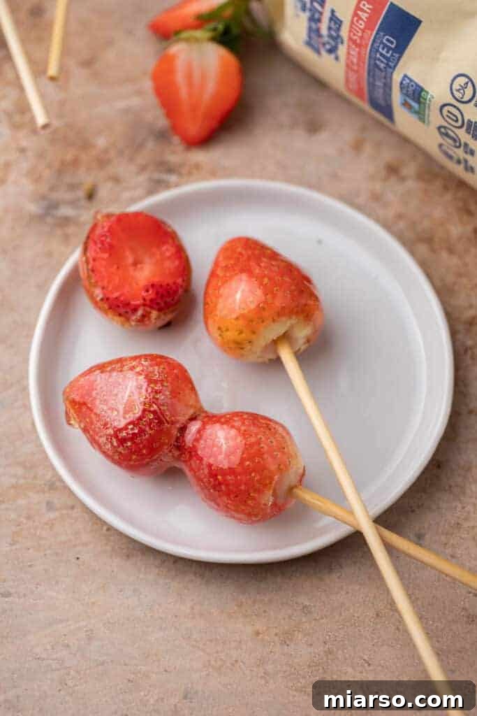 Tanghulu recipe using strawberries displayed elegantly on a white plate, highlighting their perfect candy coating.