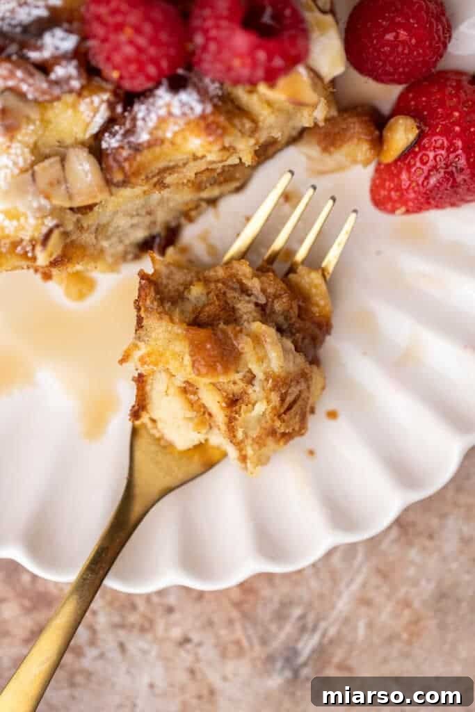 A fork holding a bite of brioche French toast, showing the custardy interior.