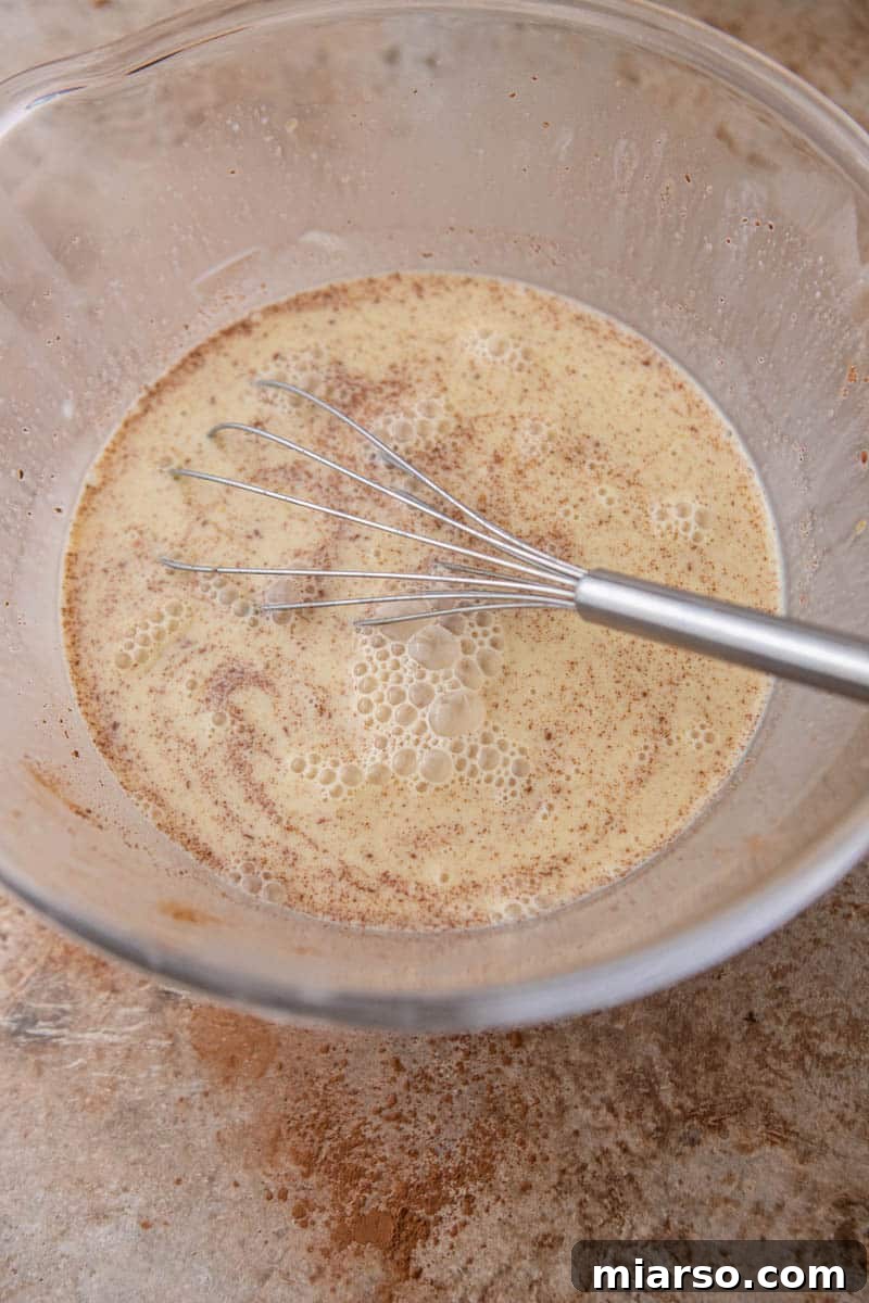 Vanilla egg custard being whisked in a glass bowl.