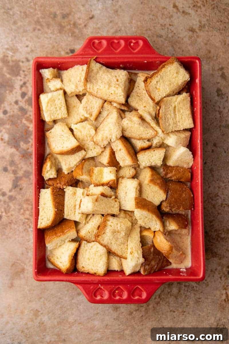 Brioche bread cubes soaking in egg custard in a baking dish.