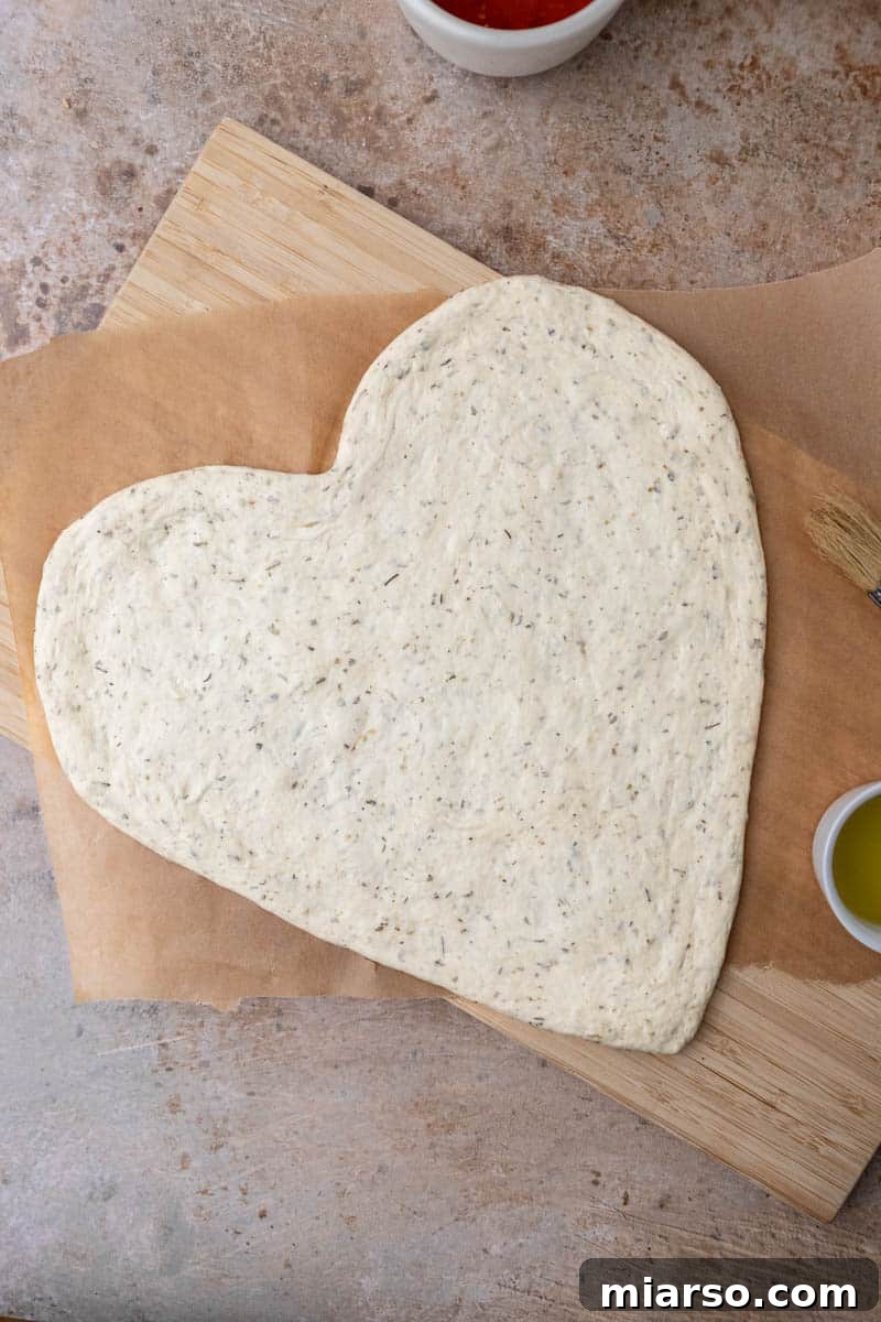 Close-up of hands delicately shaping heart-shaped pizza dough