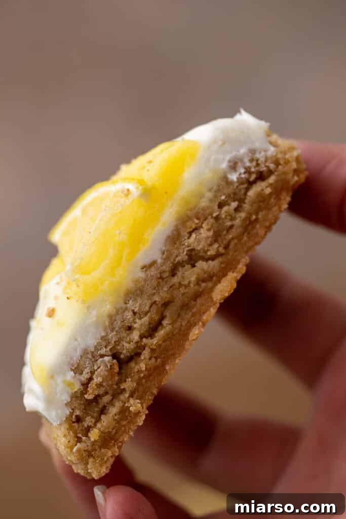 Luscious Lemon Crumbl Cheesecake Cookies 12 Sliced lemon cheesecake cookie held in hand