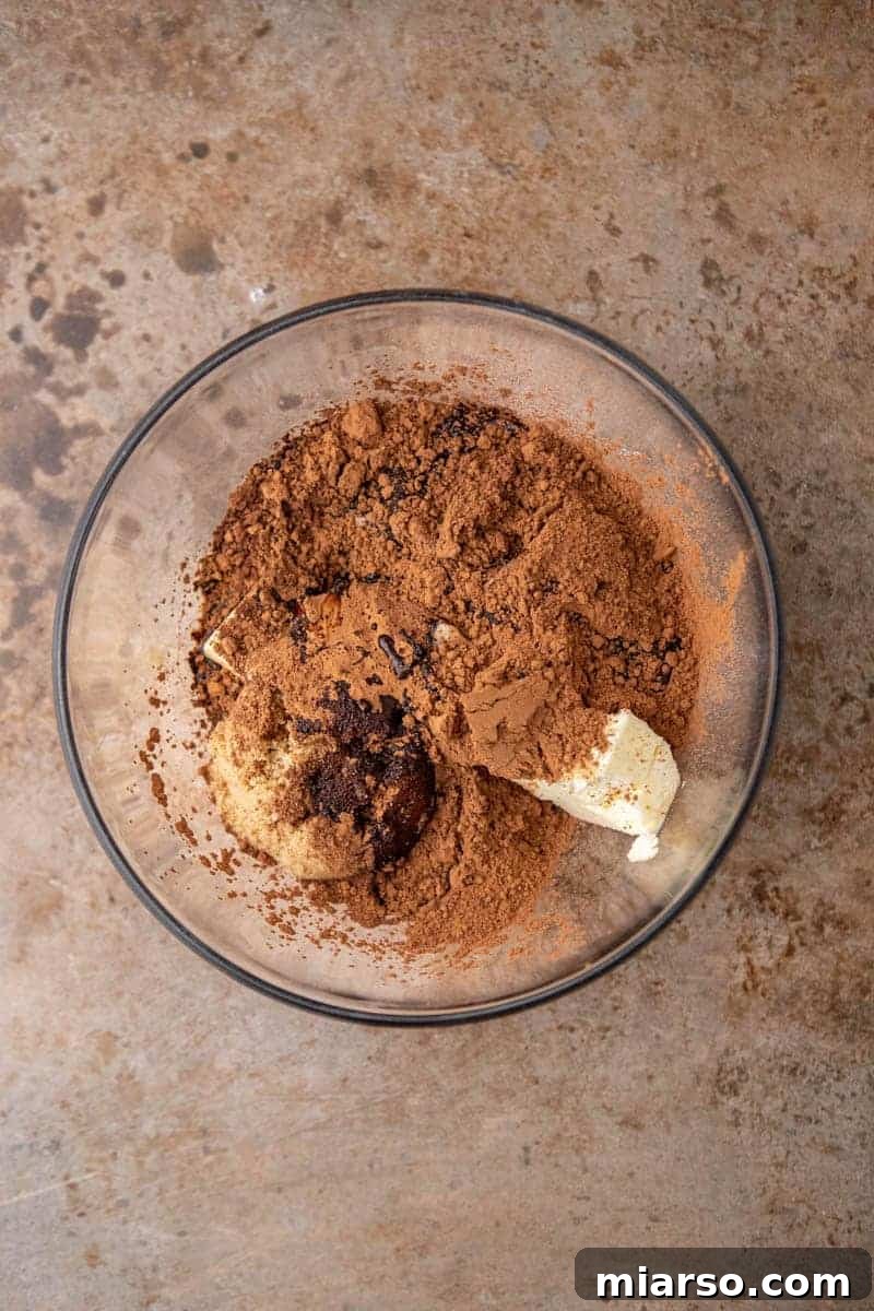 Decadent Oreo Fudge Brownies 5 Melted butter, oil, sugars, and cocoa powder in a bowl, wet ingredients for fudgy Oreo brownies.