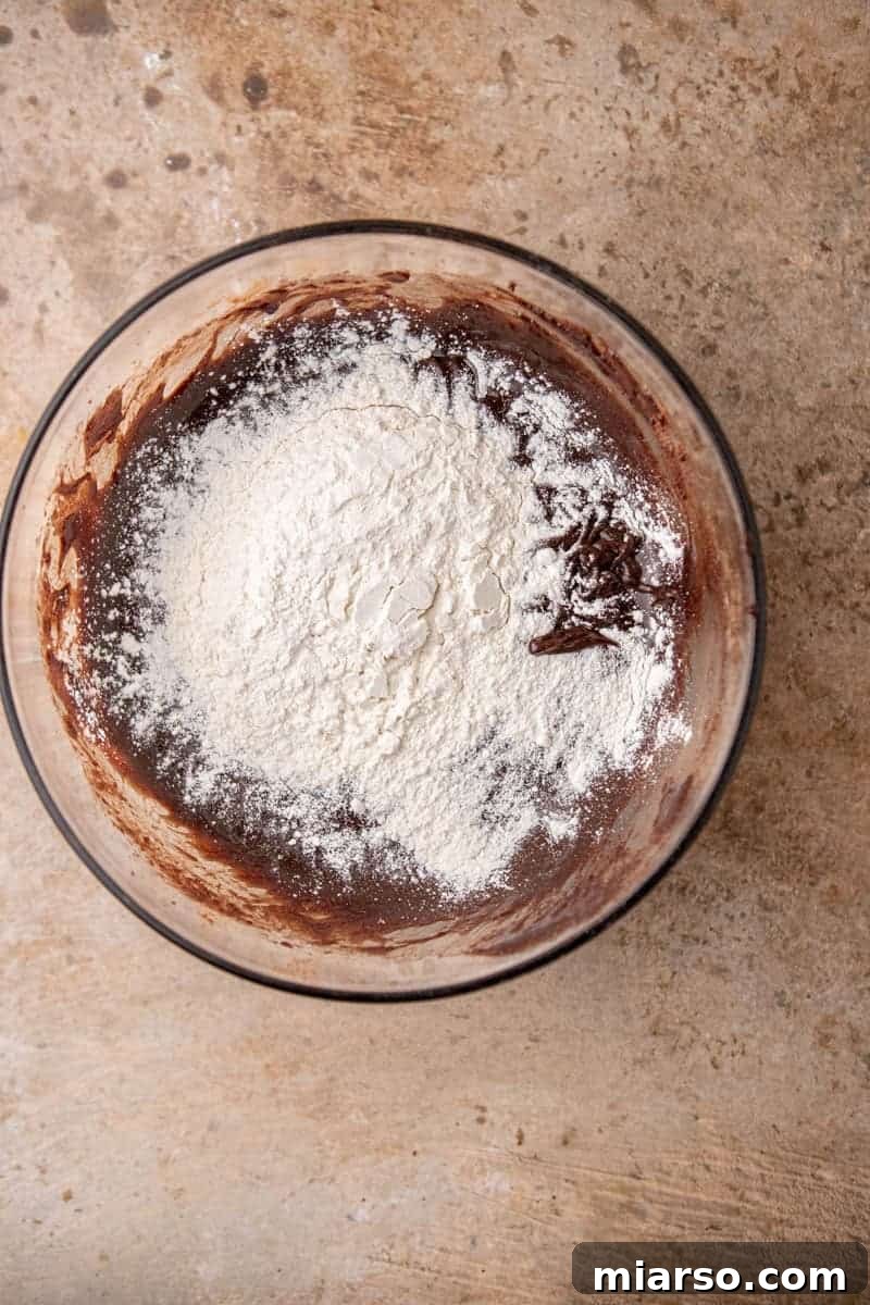 Decadent Oreo Fudge Brownies 6 Wet brownie ingredients mixed with flour in a bowl, showing the thick batter consistency.