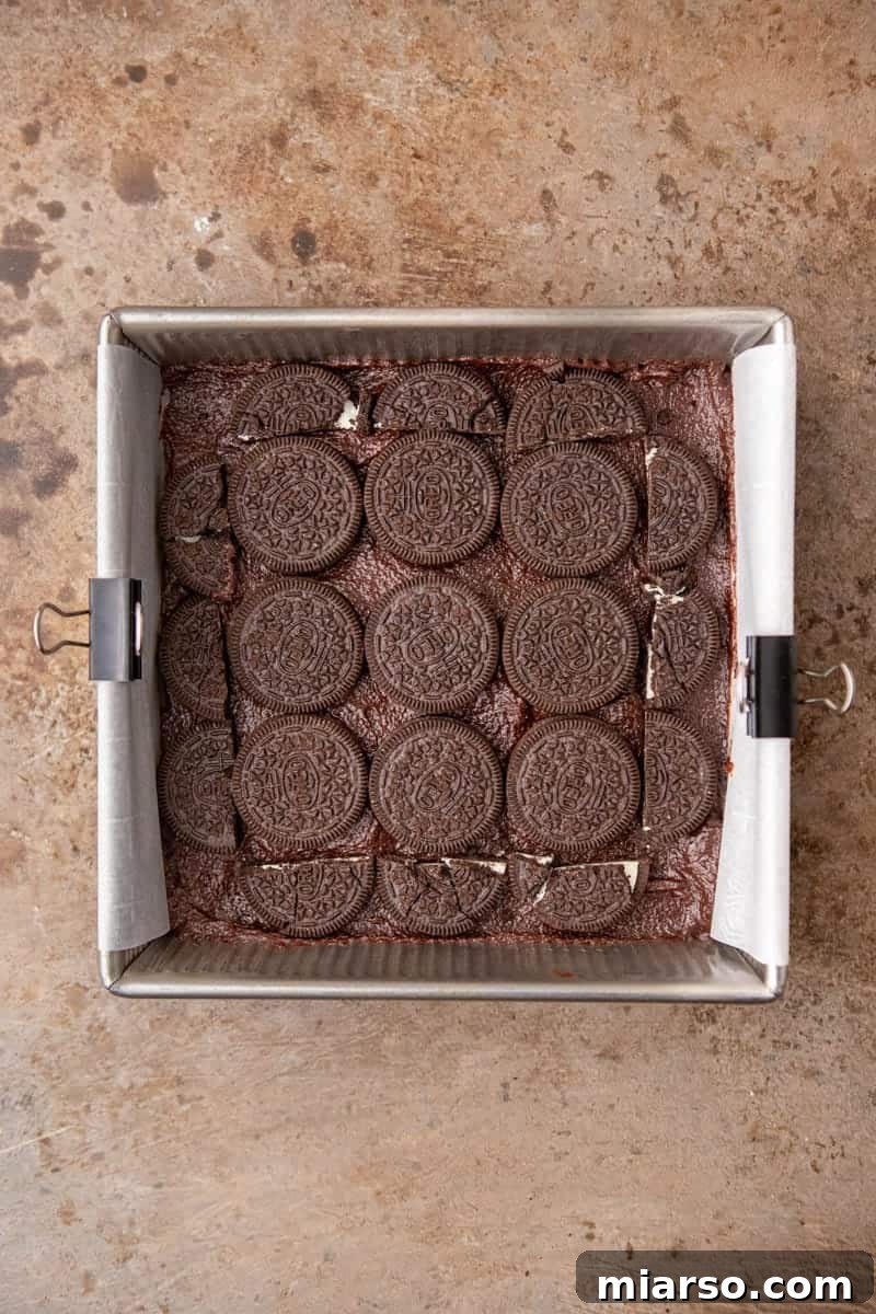 Decadent Oreo Fudge Brownies 8 Layered brownie batter with whole Oreo cookies arranged in the center of a baking pan.
