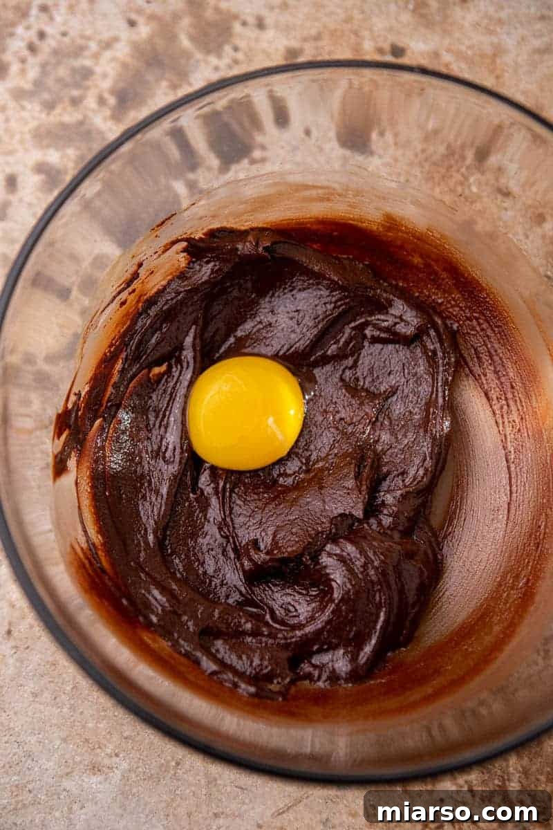 Melted chocolate mixed with egg yolk in a bowl