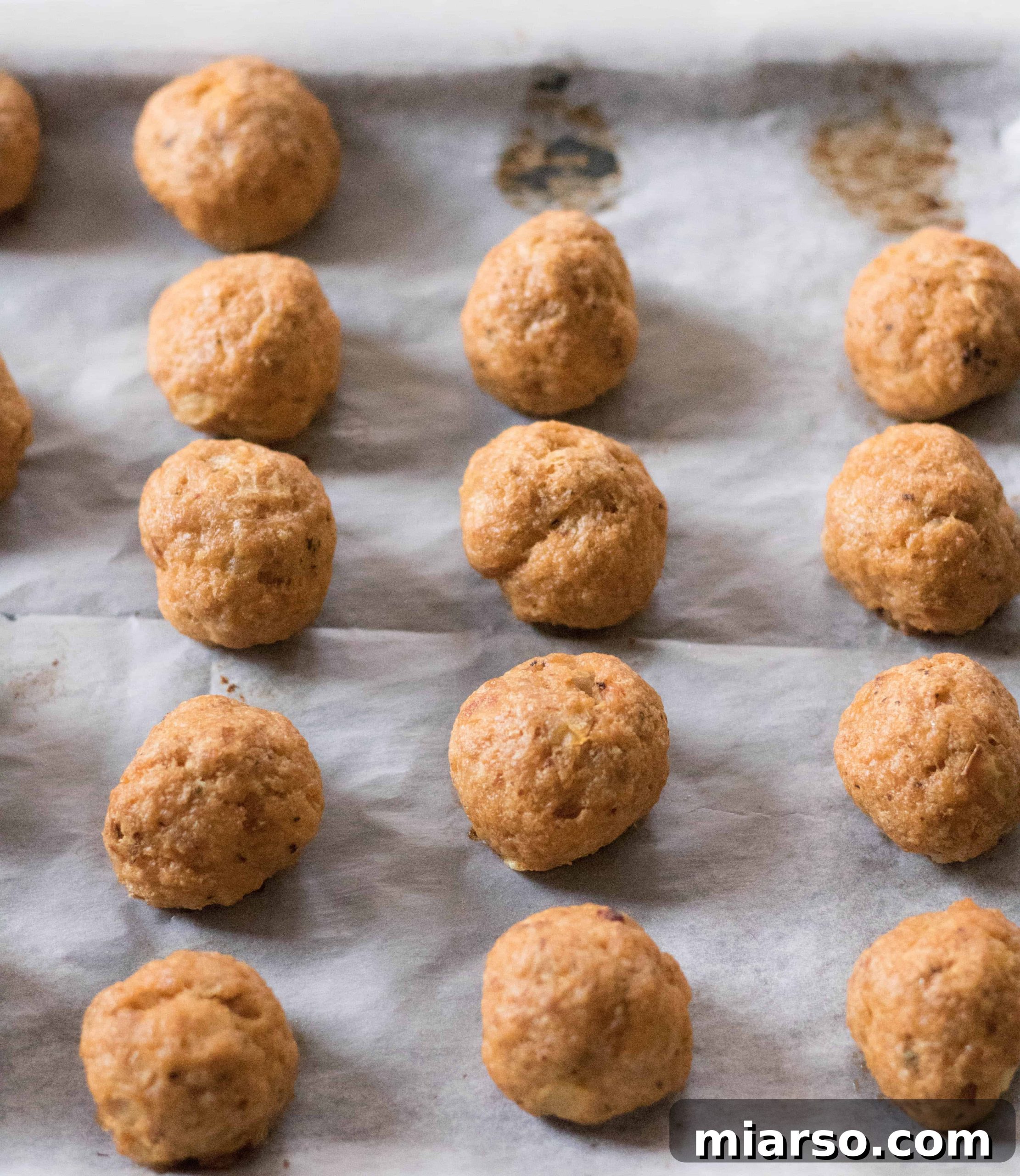 Close-up of several healthy baked buffalo chicken meatballs in a bowl, with some already taken.