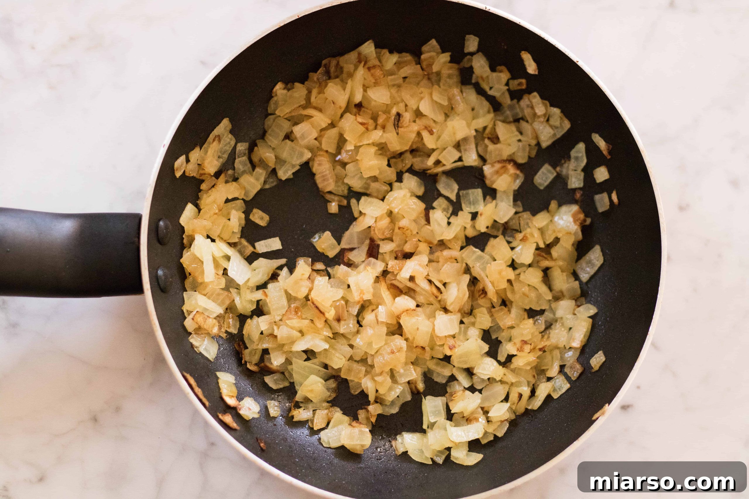 Mincing and sweating onion in a pan, a foundational step for flavor.