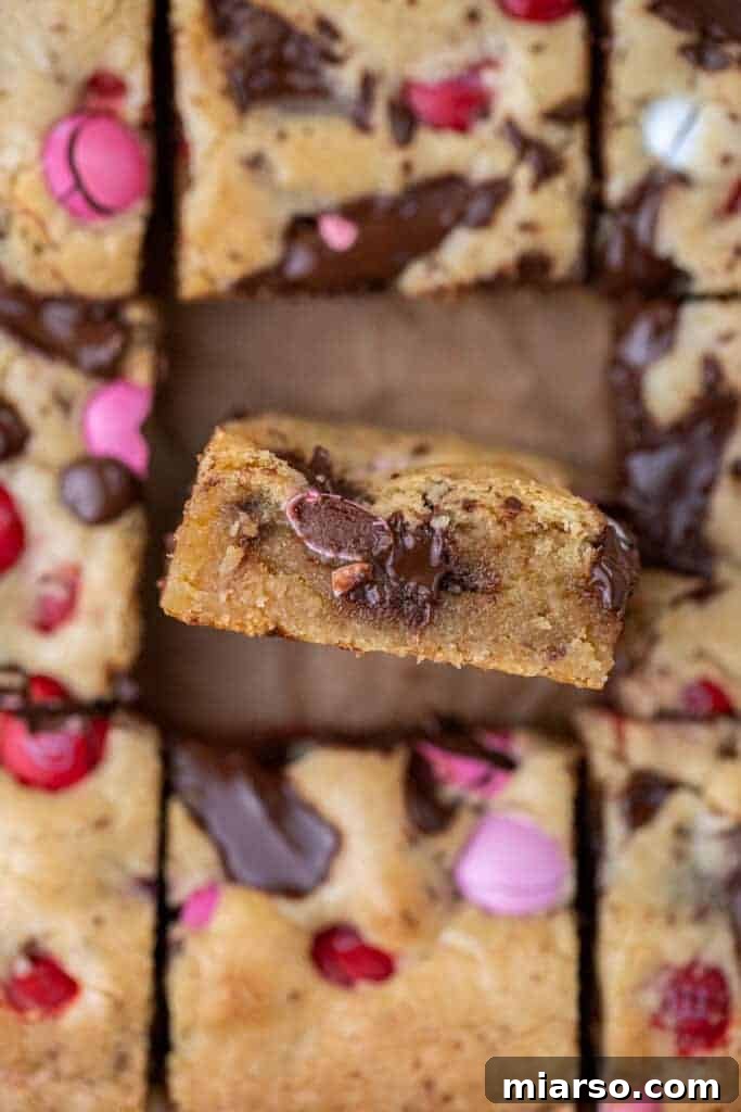 Close-up of a perfectly sliced chewy blondie bar, showing melted chocolate and M&M's inside