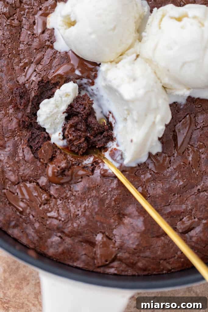 A perfectly baked, warm skillet brownie in a cast iron pan, ready to be served.