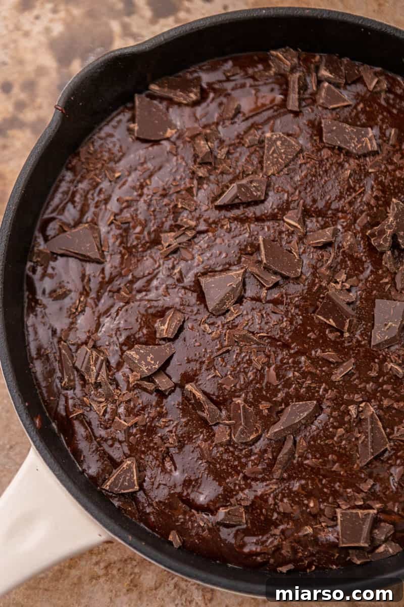 Brownie batter poured into a cast iron skillet, ready for baking.