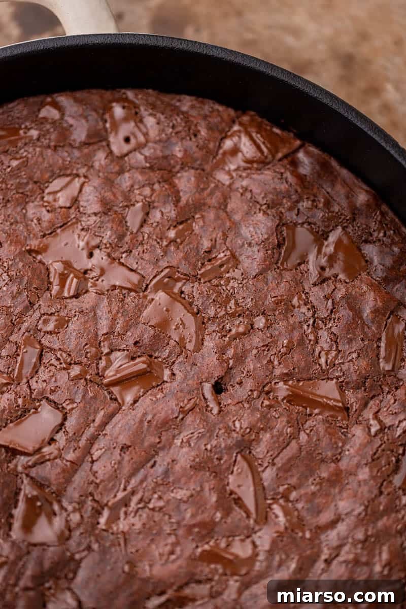 A freshly baked, shiny crinkly-top brownie in a skillet.