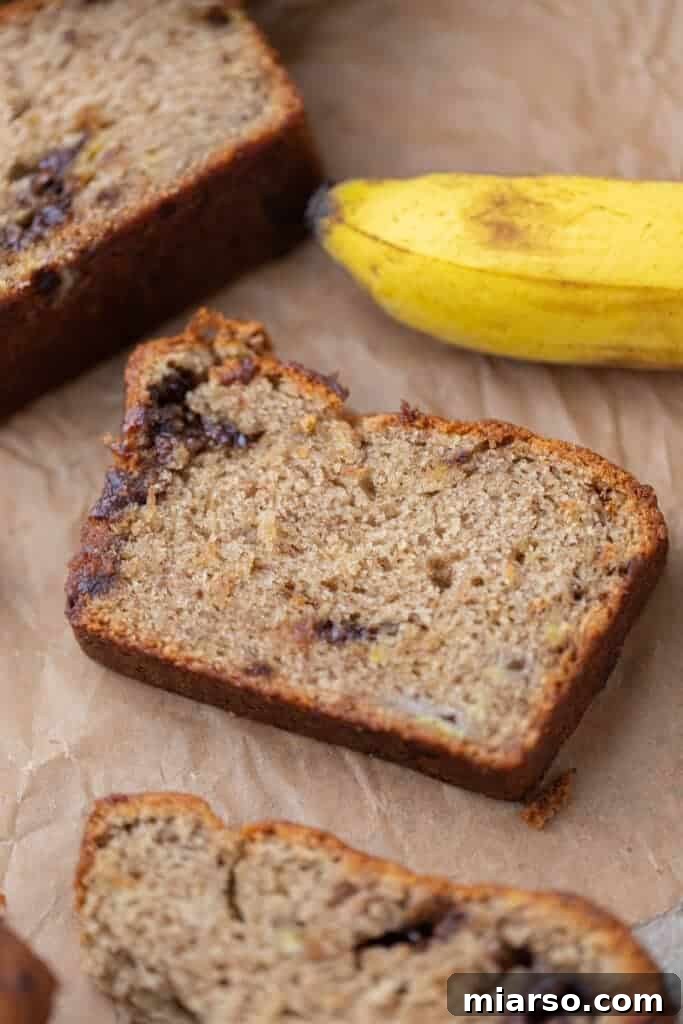 A perfectly sliced piece of moist eggless banana bread with a golden brown crust