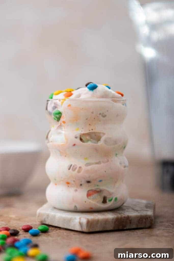 Homemade M&M's McFlurry in a clear cup with a spoon.