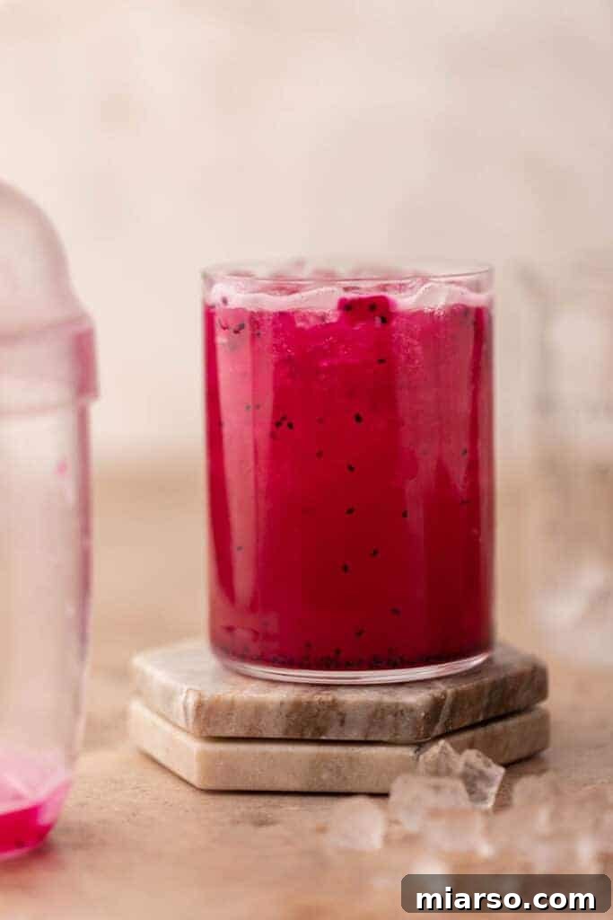 Homemade Starbucks Mango Dragonfruit Refresher in a glass with dragonfruit pieces and ice