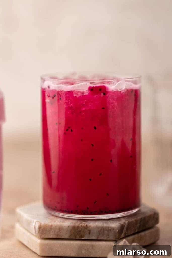 Starbucks Mango Dragonfruit Refresher in a tall glass with a straw