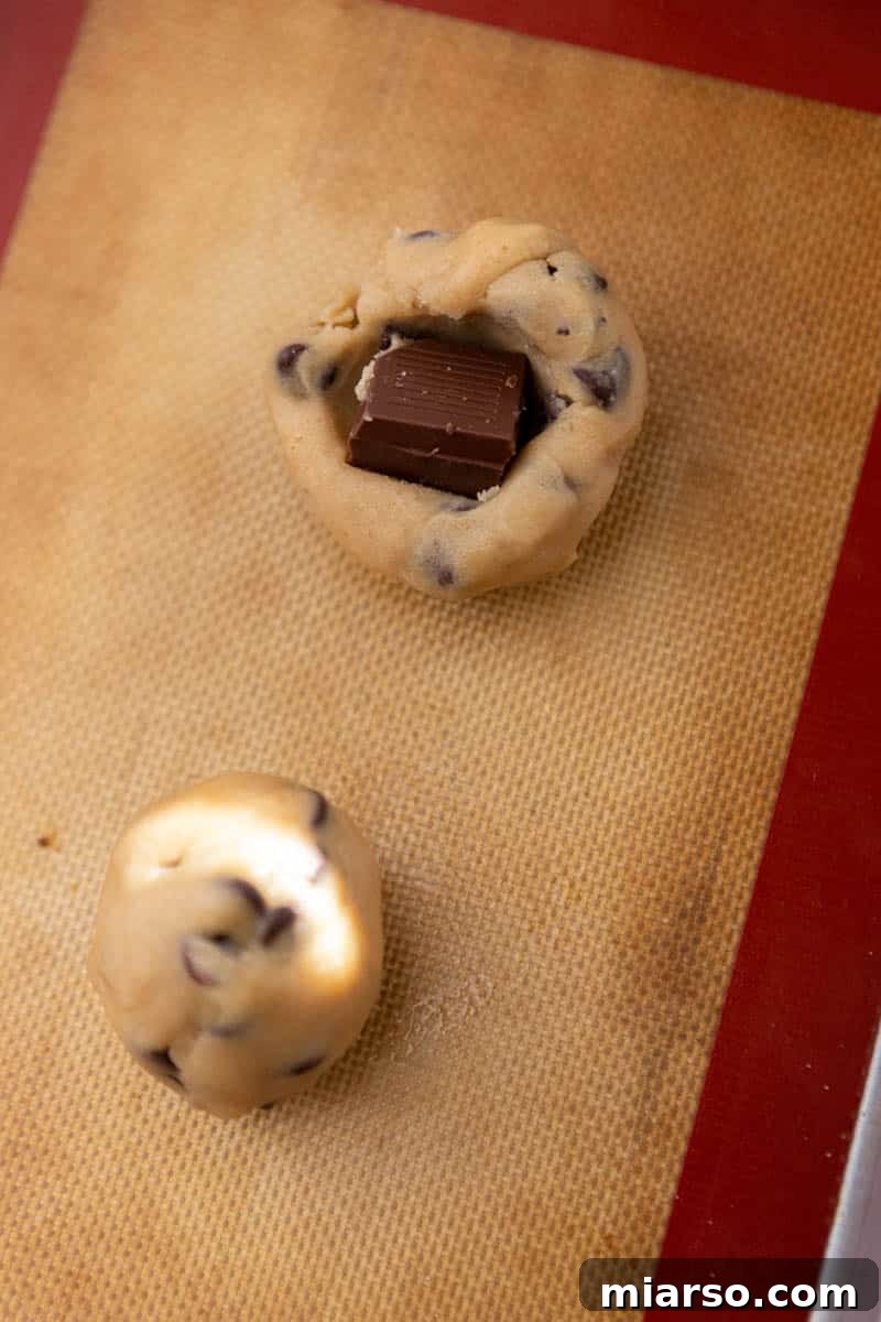 Chocolate square being stuffed into chocolate chip cookie dough