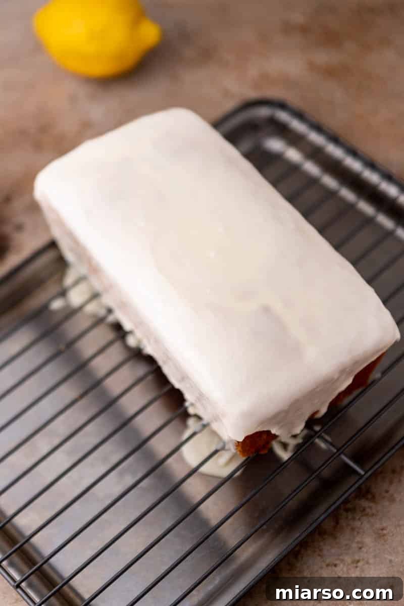 A freshly glazed lemon loaf cake, showcasing the thick, white lemon glaze.