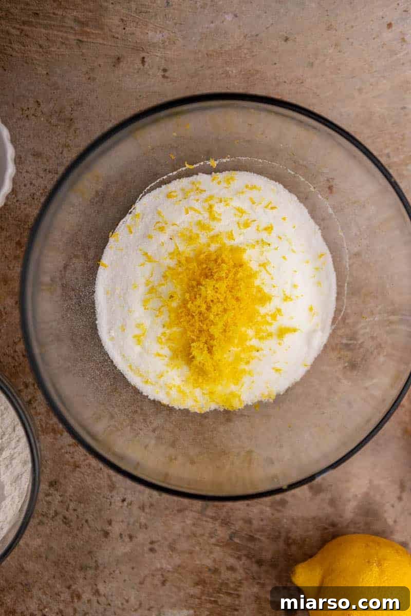 Granulated sugar being infused with lemon zest in a bowl.