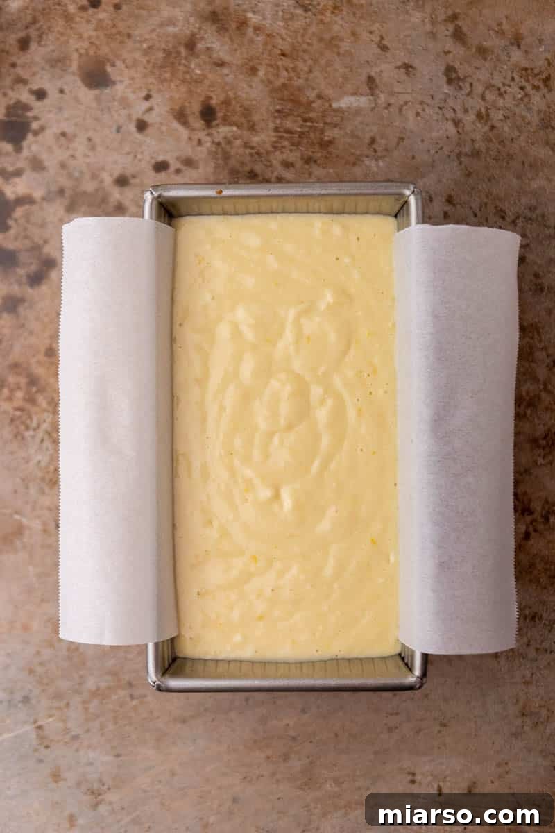 Lemon loaf cake batter poured into a prepared loaf pan, ready for baking.