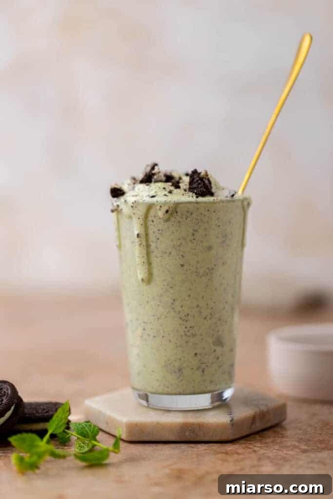 DIY McDonalds Shamrock Oreo McFlurry 2 Oreo Shamrock McFlurry with a spoon in it, featuring creamy green ice cream with cookie chunks