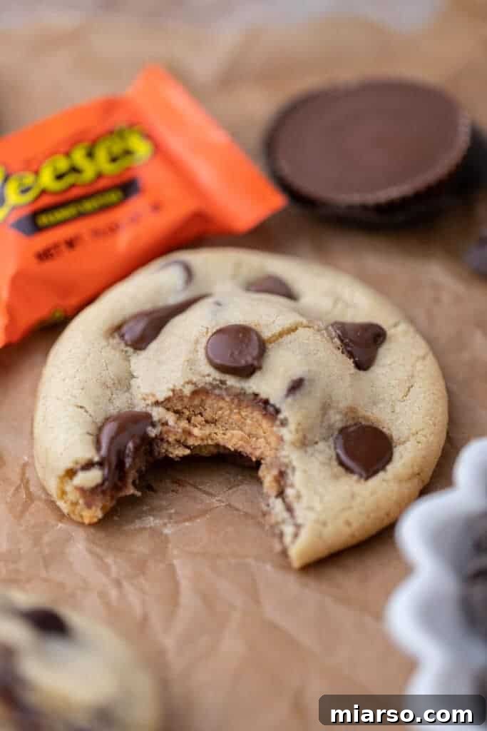 Quick Reese Peanut Butter Cup Chocolate Chip Cookies 11 A stack of Reese's stuffed chocolate chip cookies with a bite taken out of the top one, revealing the melted peanut butter center.