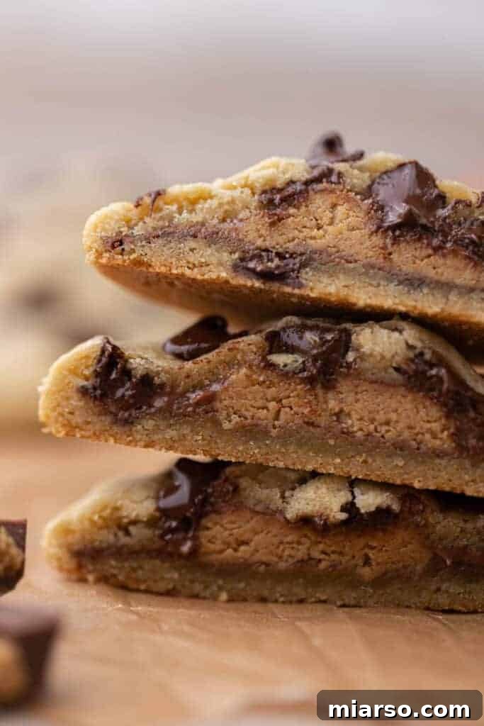 Quick Reese Peanut Butter Cup Chocolate Chip Cookies 4 Close up image of warm, freshly baked Reese's stuffed chocolate chip cookies, showing the melted peanut butter cup inside.