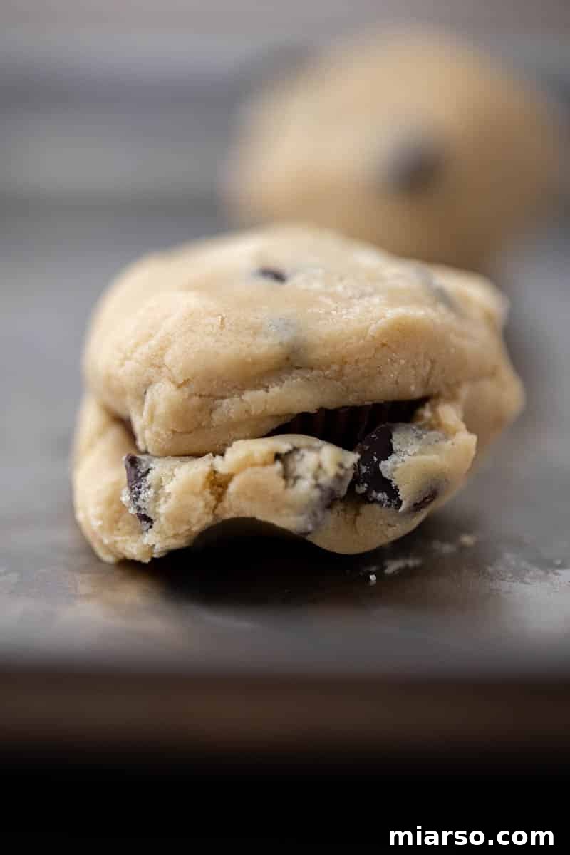 Quick Reese Peanut Butter Cup Chocolate Chip Cookies 9 Reese's stuffed chocolate chip cookie dough balls on a baking sheet before baking.