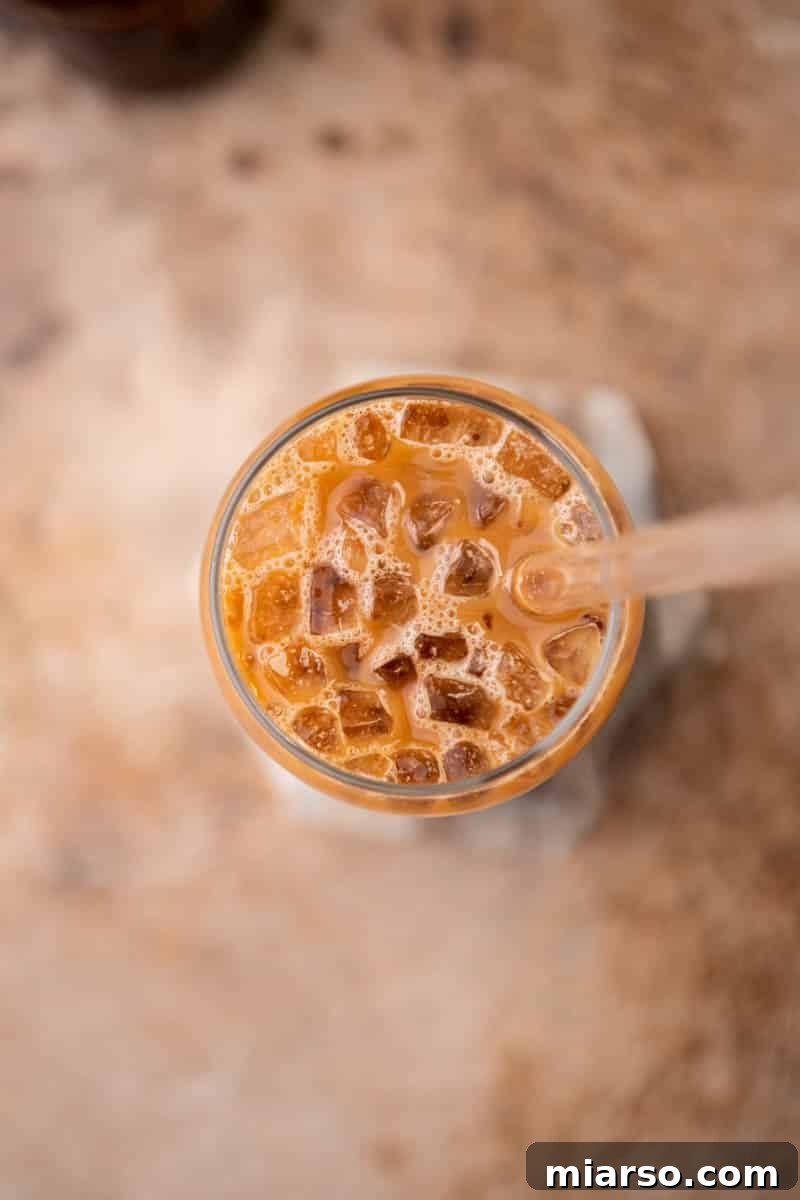 A close-up of a beautifully layered iced mocha latte with ice and milk, showing the rich chocolate and coffee base.