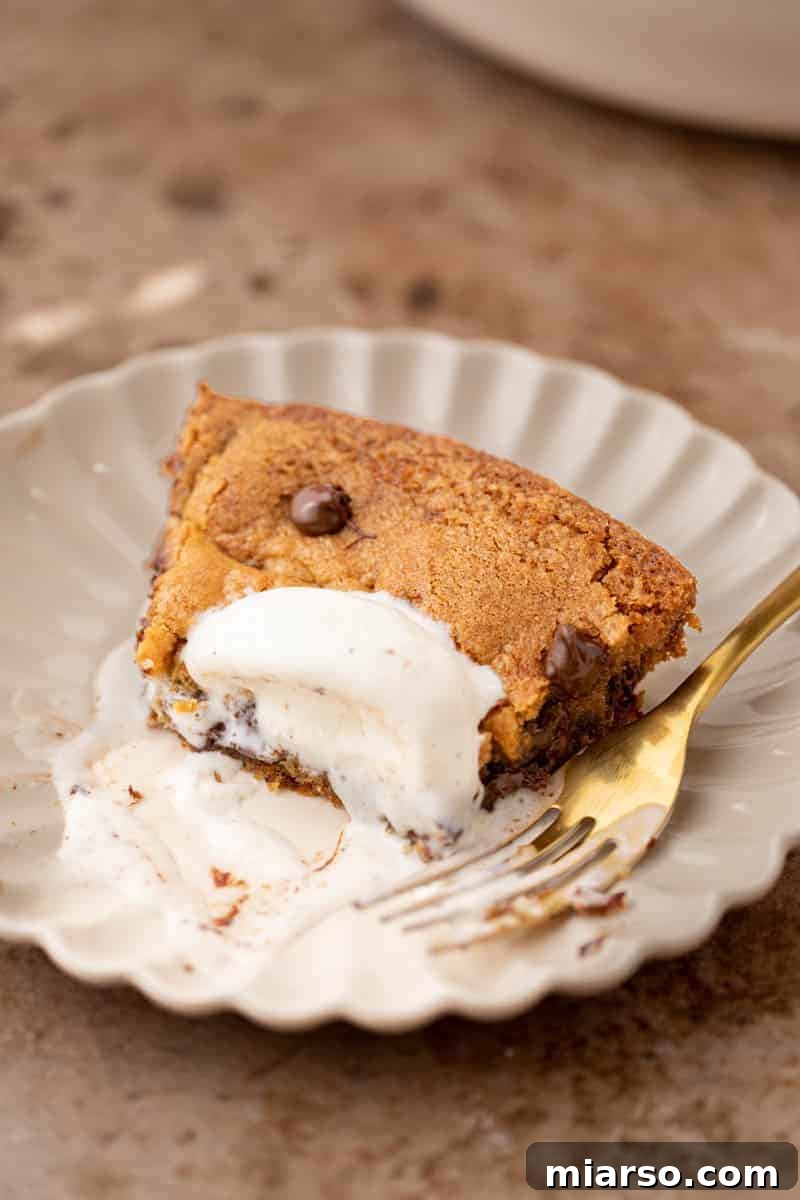 Gooey Skillet Chocolate Chip Pizookie 13 A perfectly portioned slice of skillet cookie on a white plate, ready to be enjoyed.