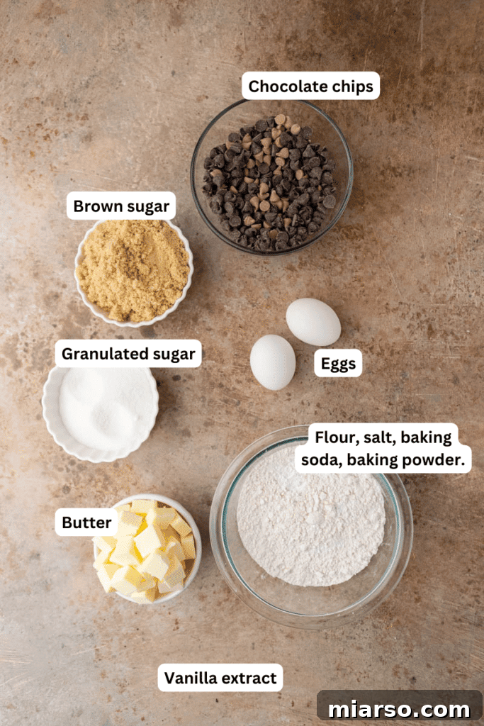 Gooey Skillet Chocolate Chip Pizookie 3 Fresh ingredients laid out on a kitchen counter, including butter, brown sugar, granulated sugar, eggs, vanilla extract, flour, baking soda, baking powder, salt, and chocolate chips, ready for making a skillet cookie.