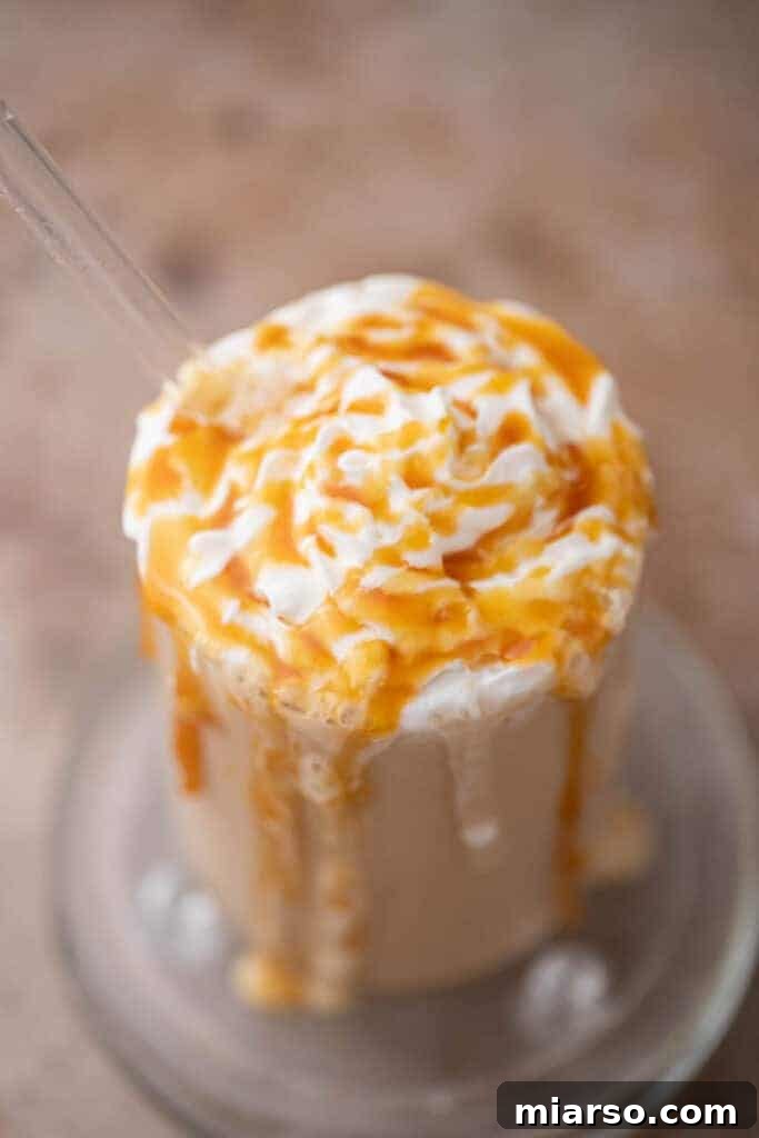 Top view of whipped cream swirled with caramel sauce on a caramel frappe