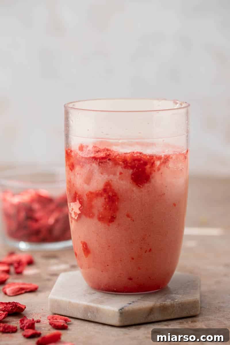 Adding ingredients to a shaker cup for pink drink