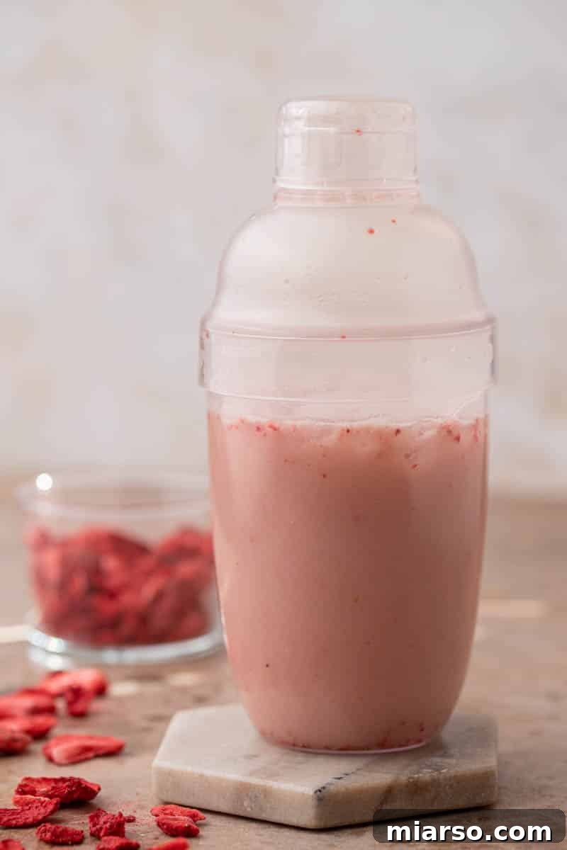 Shaking pink drink ingredients in a cup