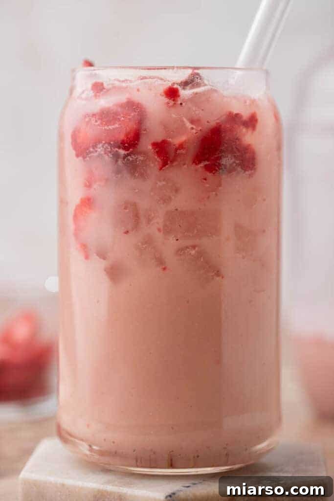 Close up of the Starbucks pink drink in a tall glass with strawberries and ice