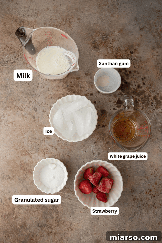 Ingredients for homemade Starbucks Strawberry Frappuccino laid out on a kitchen counter, including milk, strawberries, grape juice, and ice.