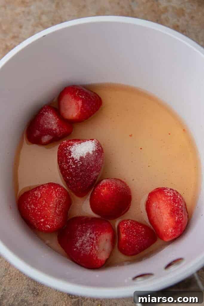 Strawberries and grape juice simmering in a pan, beginning to form the sauce.
