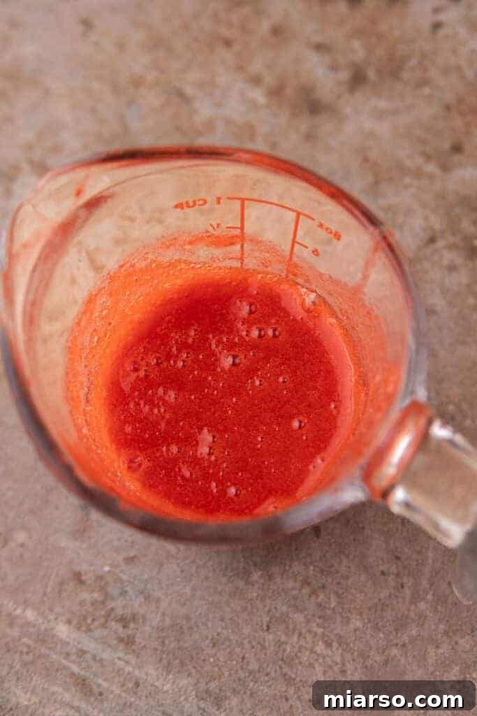 Smooth strawberry sauce transferred to a cup, ready for chilling.