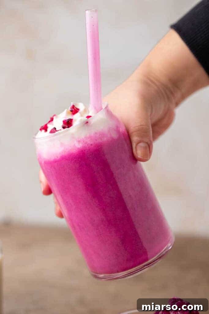 Hand holding Starbucks Barbie Frappuccino, a vibrant pink drink.