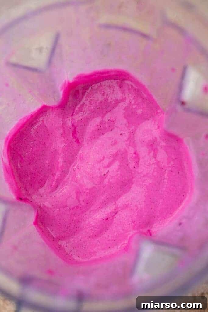 Pink frappuccino mixture blending in a high-speed blender.