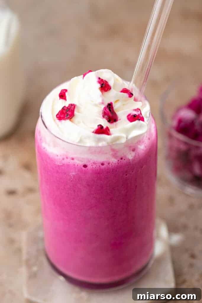 A vibrant pink frappuccino in a clear glass, showing its creamy texture.