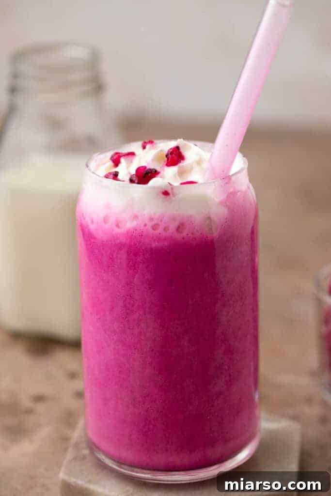 Close-up shot of a Barbie Frappuccino, showcasing whipped cream, dragon fruit pieces, and the pink drink.