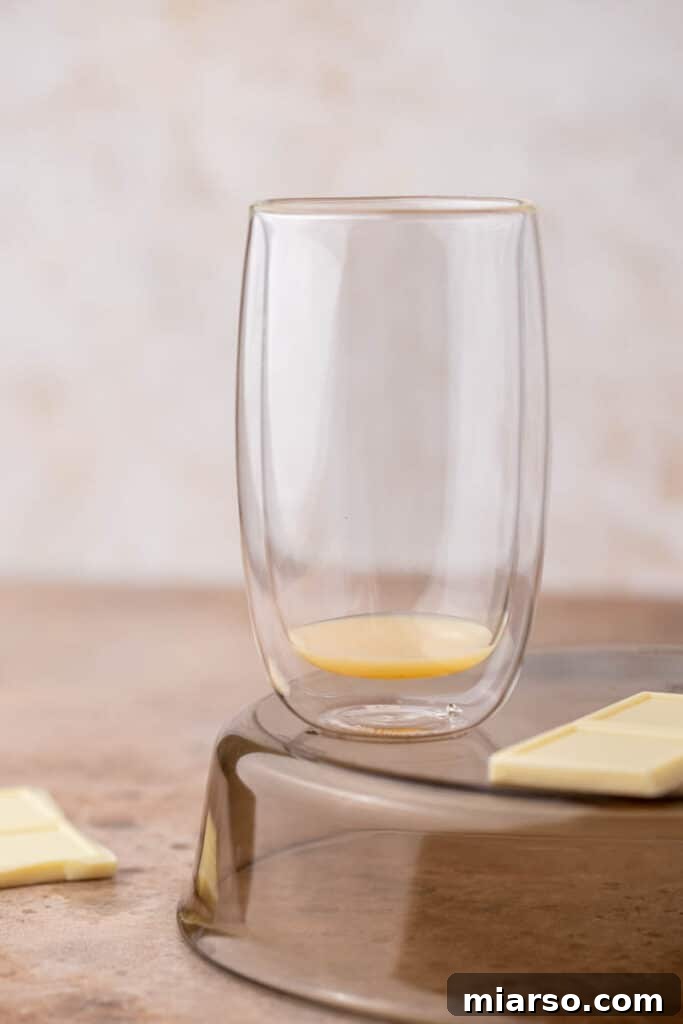 White chocolate sauce being poured into a clear glass