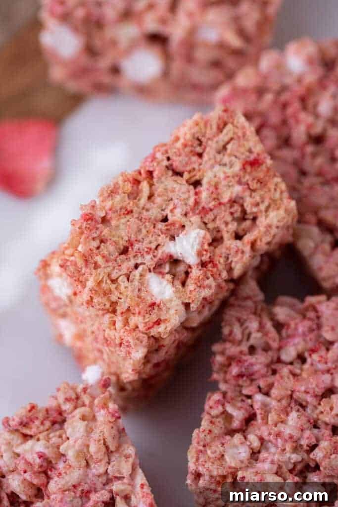Plate of strawberry rice krispies treats garnished with fresh strawberries.