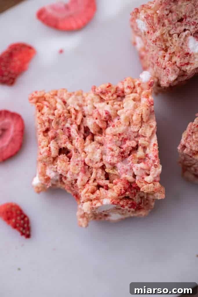 A slice of strawberry rice krispies treat with a bite taken out, showing its chewy interior.