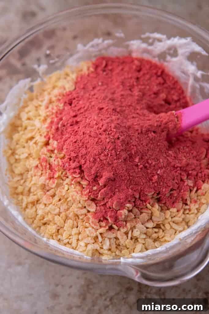 Rice Krispies cereal and freeze-dried strawberry powder mixed in a bowl.