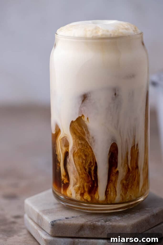 Close up of luscious vanilla sweet cream cold foam swirling on top of a cold brew coffee