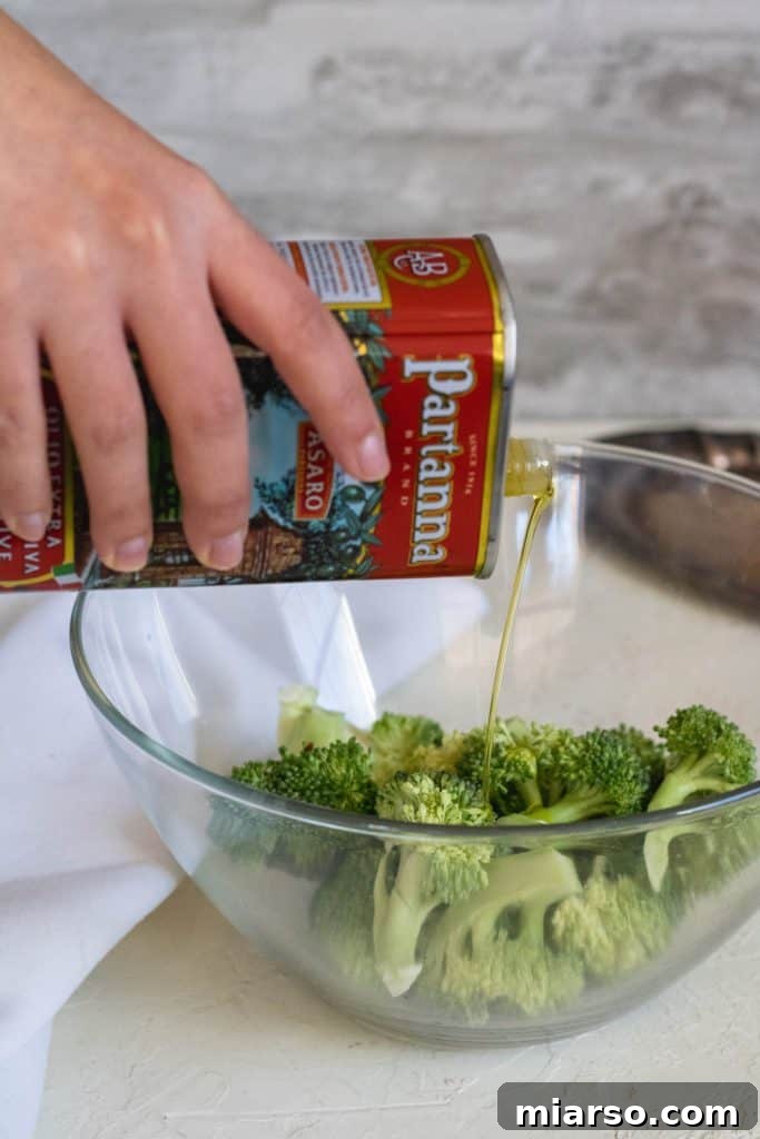 Partanna olive oil poured over broccoli florets in a mixing bowl
