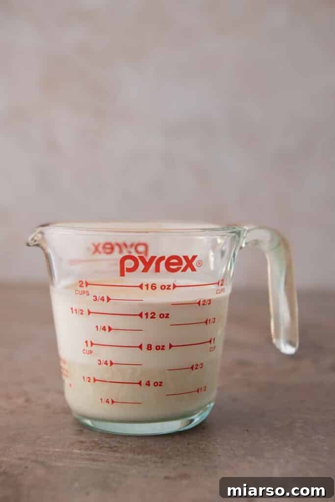 Sweetened condensed milk being poured into a measuring cup.
